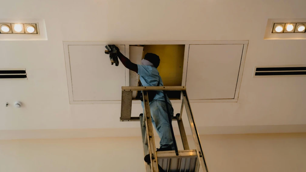 man con ladder doing duct work